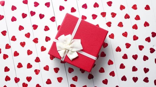 Festive Present Surrounded by Heart Confetti