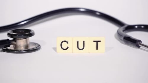 Medical Stethoscope Next to Block Letters Spelling Cut