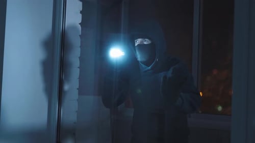 Masked Person at Window at Night with Flashlight