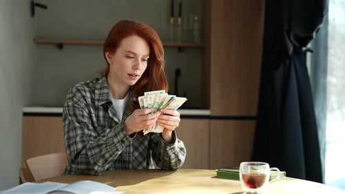 Concept of Financial Crisis Desperate Young Woman Counting Money with Sad Expression Sitting at