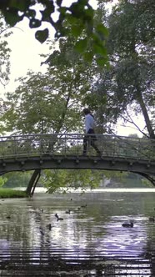 Vertikale Seitenansicht zweier verliebter junger Menschen, die durch eine kleine Brücke im Park über dem