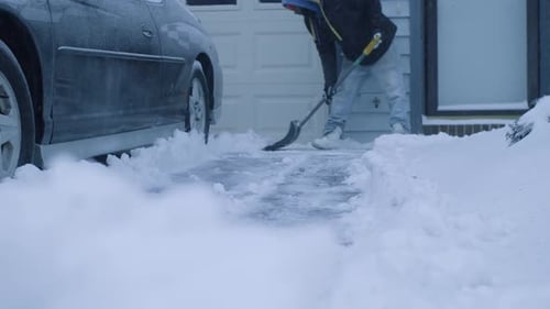 Plowman plowing snow near car behind garage