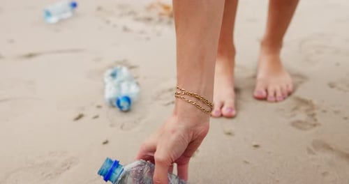 People, hands and beach with plastic bottle for recycling, cleaning or saving the planet in nature