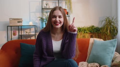 Eine nachdenkliche, inspirierte junge Frau, die Eureka-Geste macht, hebt den Finger und hat sich zu Hause einen kreativen Plan ausgedacht