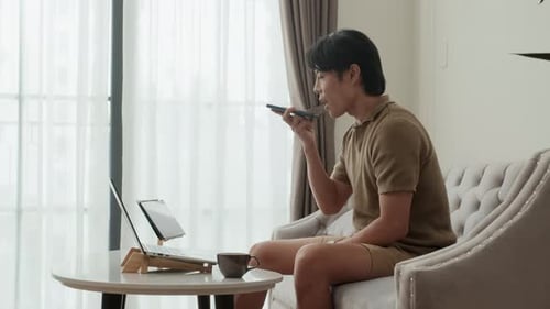 Man Uses Laptop and Cellphone on Couch