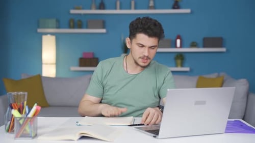 Young Adult Man Works from Home on Laptop