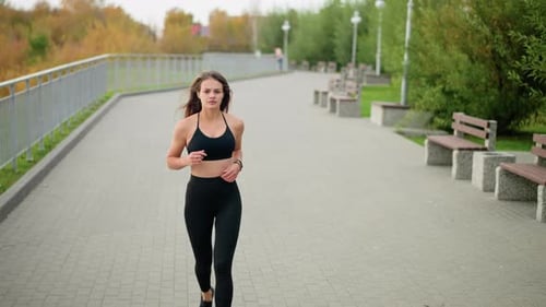Pretty Woman Jogging in Black Sportswear and Wristwatch in Park