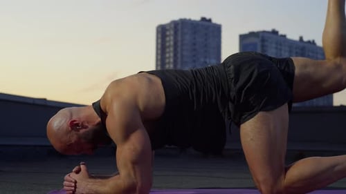 Athletic Man Doing Leg Exercises on Rooftop at Sunrise