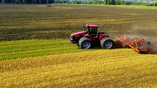 Tractor plowing field, agriculture farmland from aerial perspective