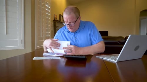An older man works on his taxes or bills from home - sliding
