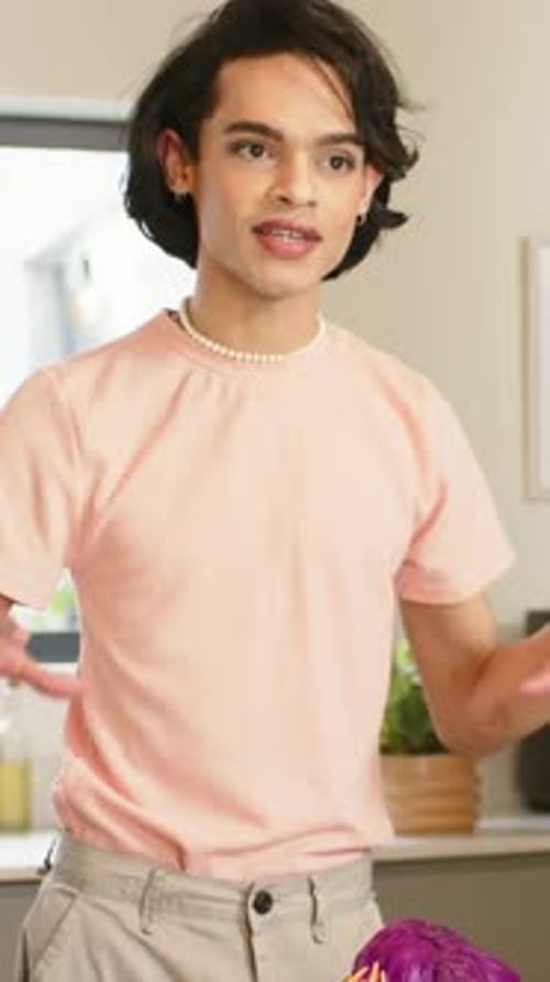 Vertical video: Starting man in pink tee rubbing palms and showing salad prep at counter with knife