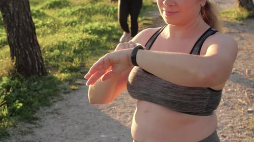 Woman Checking Fitness Tracker on Park Path