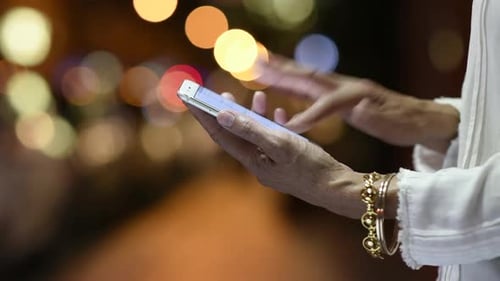Elegant woman hands texting on mobile phone in city street nightlife