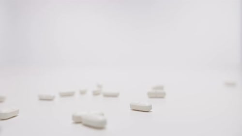 Different kinds pills falling on white background in slow motion