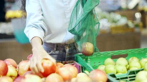 Primer plano de una joven selecciona a mano y coloca los picos en una bolsa ecológica de verduras o frutas en un supermercado