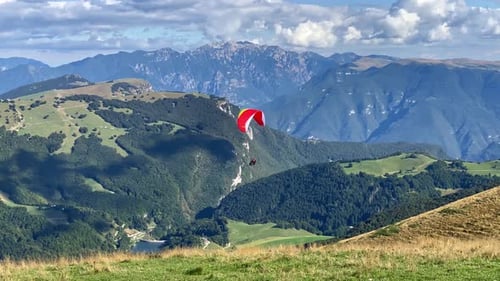 Gleitschirmflieger starten und über Bergen fliegen