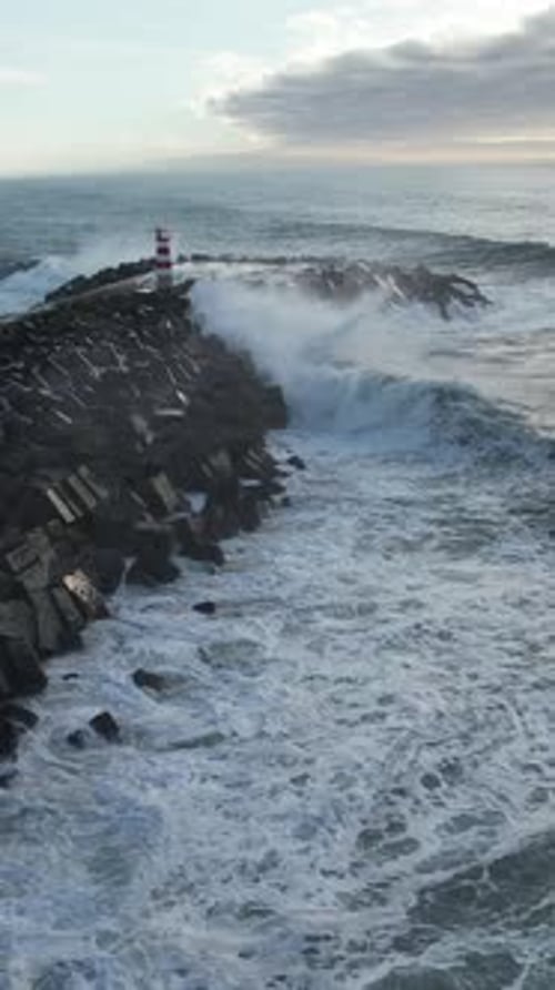 Vertical Video of Waves Crashing on the Pier Rocks Aerial View