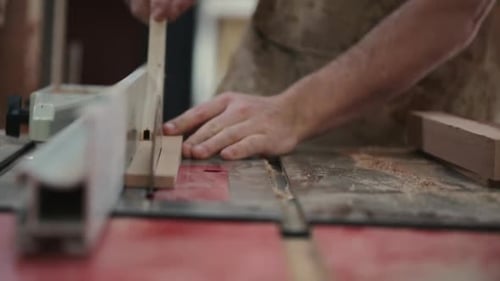 Mid adult carpenter carefully cutting wood block with a table saw in calgary alberta