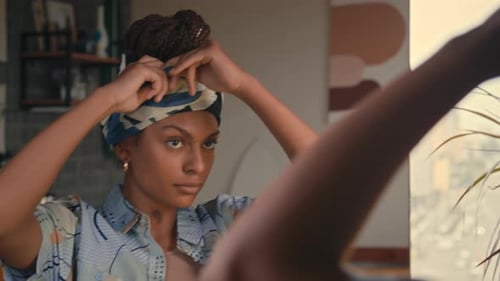 Woman Tying Headscarf in Mirror Indoors
