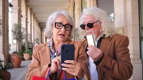 Senior couple using phone and credit card shopping online