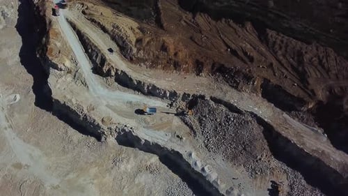 Gelber Bagger, der auf der Baustelle Erde in einen Muldenkipper lädt