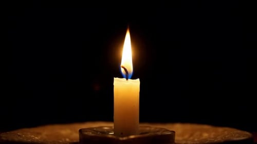 Einzelne brennende Kerzenflamme auf dunklem Hintergrund