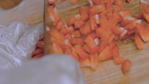 Front View of the Young Chef Cut Thin Slices of a Piece of Red Pepper with a Knife on the Cutting