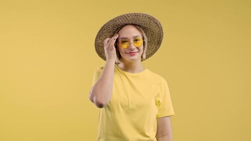 Playful Blonde Woman Smiling Flirting to Camera on Yellow Studio Background
