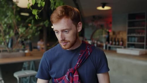 Portrait of Successful Young Caucasian Man with Ginger Hair Charming Smile Sitting in Cafe for