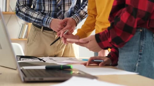 Three People Point at Graphs in Office