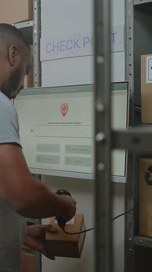 African American Parcel Processing Specialist Checks Delivery Information at Postal Terminal