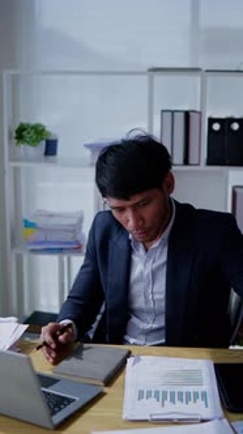 Man Reviews Financial Documents at Office Desk