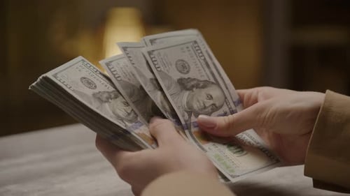 Hands Counting Stack of One Hundred Dollar Bills