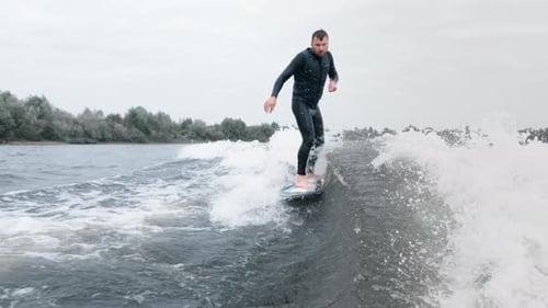 Man Wake Surfing on a Lake on Overcast Day