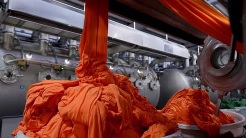 Orange Fabric Moving Through Industrial Dyeing Machine