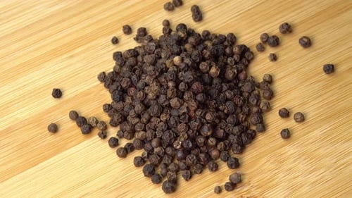 Pile of Whole Black Peppercorns on Wood Surface