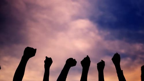 Silhouetted Fists Raised in Protest Against Sky