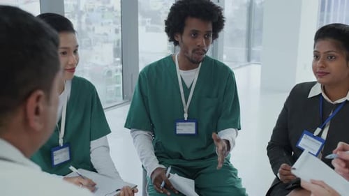 Male Nurse Communicating with Colleagues during Meeting in Hospital