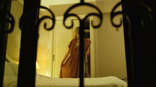 à noite, no quarto, uma mulher experimenta um vestido