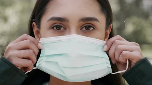 Young Middle Eastern Woman Puts on a Face Mask Outdoors in a Park