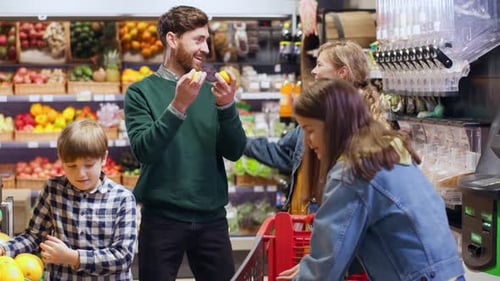 Young Caucasian Family with Two Siblings Shopping Food in Grocery Store Choosing Fresh Food Items