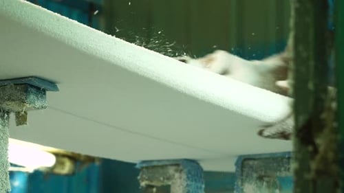 Slow motion man's hands smoothing DIY surf foam board in workshop with sander