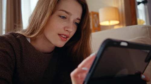 Woman Uses Tablet Device Relaxing on Couch