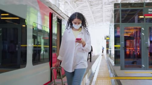 Woman Walks with Phone at Urban Train Station