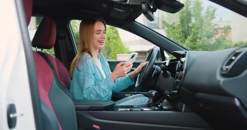 Smiling Woman Uses Phone Inside of Car