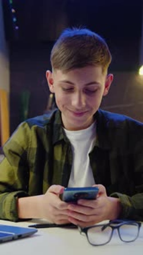 Teenager Using Smartphone While Seated at Table Indoors
