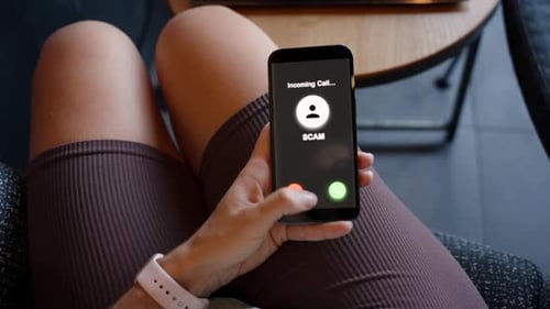 A woman decisively rejects an incoming “SCAM” call by pressing the button to turn off the screen on