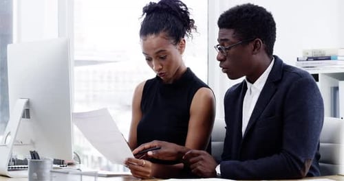 4k video footage of two businesspeople going through paperwork together in a modern office