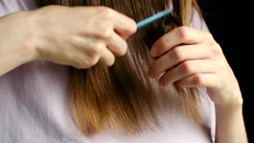 Woman Combs Light Brown Hair and Inspects Strands