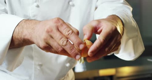 Chef Cracks Egg into Bowl in Kitchen